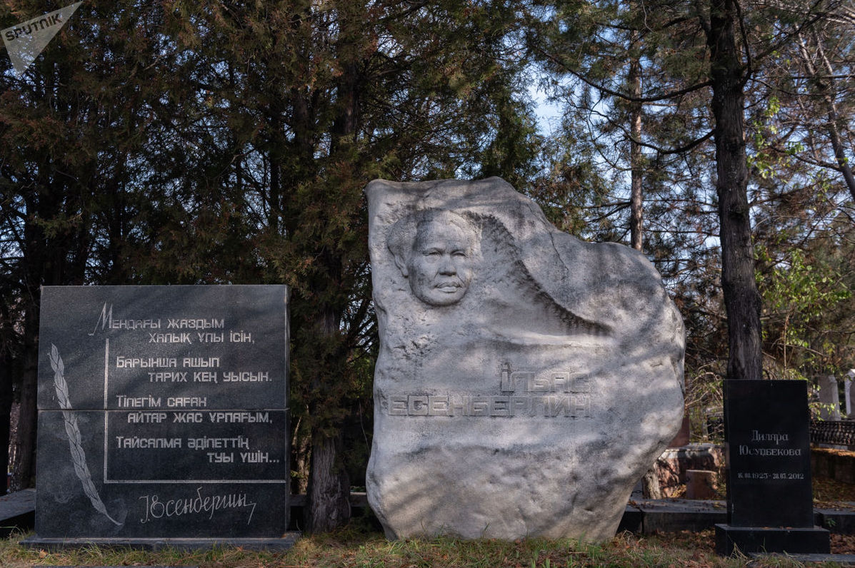 Писатель, романист Ильяс Есенберлин запечатлен в закругленном медальоне на огромном сером могильном валуне