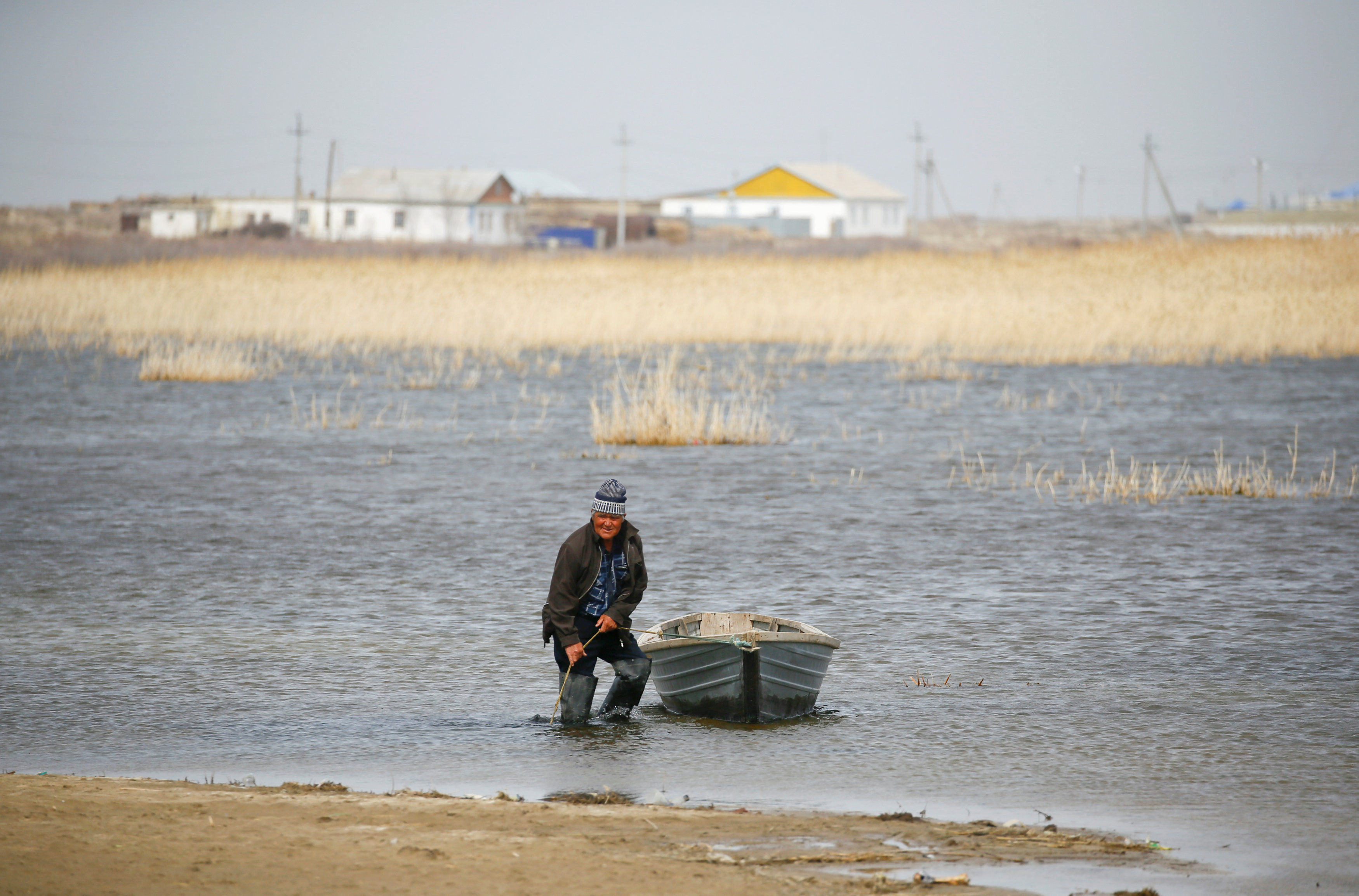 Сельский житель привязывает лодку на берегу Аральского моря,