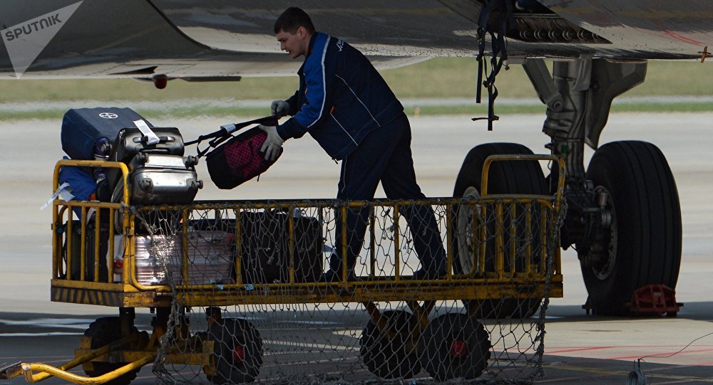 Рабочий разгружает багаж из самолета, архивное фото